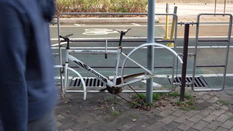 13-February-2023---Abandoned-White-Bicycle-Hanging-To-Railings-With-No-Wheels-In-Tseung-Kwan-O,-Hong-Kong