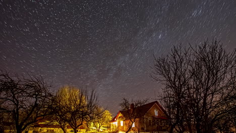 Long-Exposure-Of-Stars-Moving-At-The-Night-Sky-Over-The-Trees-And-House
