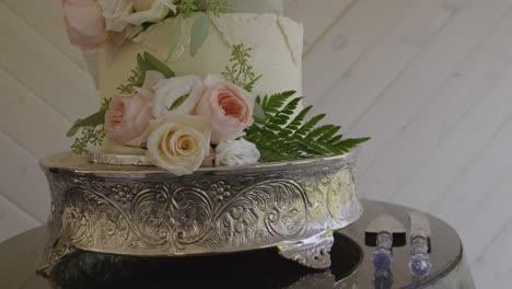 Beautiful-wedding-cake-decorated-with-natural-flowers-and-leaves,-mounted-on-a-baroque-silver-base