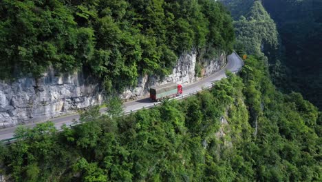 Drone-is-following-a-truck-on-the-road-driving-through-breathtaking-forests-and-canyons,-high-altitude,-and-winding-road,-captured-at-Hebei-Province,-China