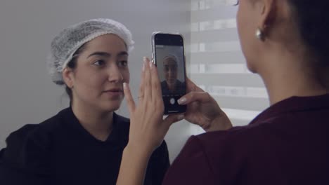 Cosmetic-surgery-patient-getting-picture-taken-with-smartphone-in-a-clinic-by-nurse,-slow-motion