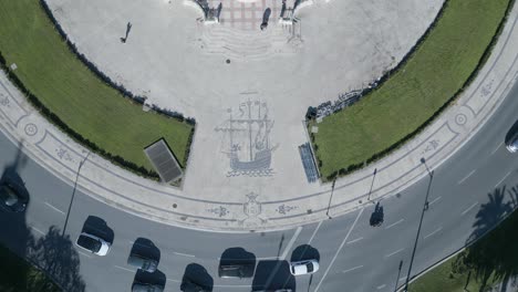 Aerial,-bottom-up,-drone-shot,-above-the-symbol-of-the-historical-caravel-in-the-middle-of-the-roundabout-of-Marques-de-Pombal-statue-in-the-city-of-Lisbon,-sunny-day,-in-Lisbon,-Portugal
