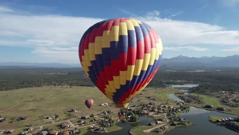 Luftaufnahme-Von-Bunten-Heißluftballons,-Die-An-Einem-Sonnigen-Sommertag-über-Grüner-Landschaft-Und-See-Fliegen
