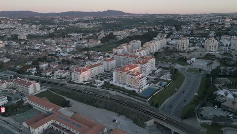 Luftaufnahme-Eines-Vorbeifahrenden-Zuges-Mit-Touristen-Und-Arbeitern-In-Der-Nähe-Des-Strandes-Von-São-Pedro-An-Einem-Sonnigen-Tag,-Portugal