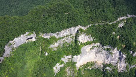 Majestic-aerial-footage-over-road-with-traffic-passing-through-a-breathtaking-forest,-high-altitude,-and-winding-road-view,-captured-in-Hebei-Province,-China