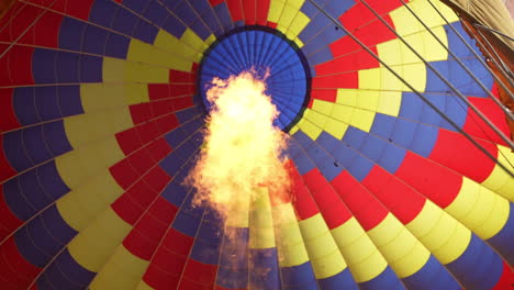 Burner-Flames-Under-Colorful-Parachute-of-Hot-Air-Balloon,-Low-Angle