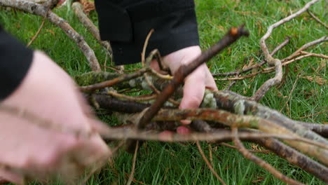 Close-up-of-a-man-picking-up-sticks-and-branches-from-the-grass-in-a-back-yard-field-garden