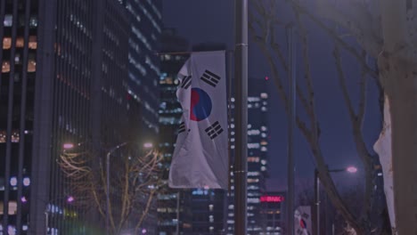 Bandera-Nacional-De-Corea-Del-Sur-Ondeando-En-La-Noche-En-La-Ciudad-De-Seúl-Ciudad-Urbana-Con-Edificios-Y-Construcciones