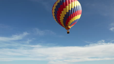 Colorful-Hot-Air-Balloon-Flying-Under-Blue-Sky-on-Sunny-Day,-Drone-Shot