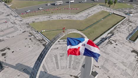 High-angle-of-flag-waving-in-the-wind,-Plaza-de-la-Bandera-at-Santo-Domingo-city,-Dominican-Republic