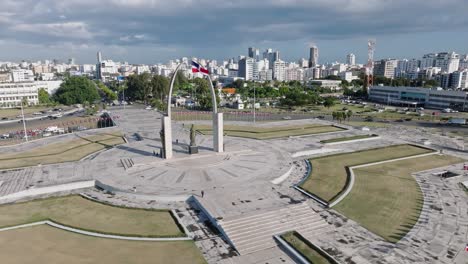 Aerial-panoramic-shot-of-traffic-on-roundabout-of-Santo-Domingo-City-during-sunlight---Memorial-on-Plaza-de-La-Bandera
