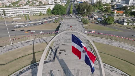 Flag-waving-in-the-wind-on-triumphal-arch,-Plaza-de-la-Bandera-at-Santo-Domingo-city