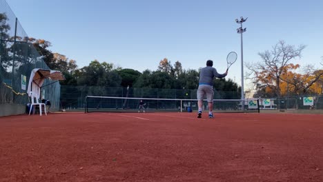 Man-playing-tennis-in-a-hardcourt-with-a-partner-in-Lisbon,-Portugal