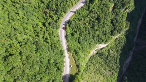 Top-view-aerial-footage-over-a-road-with-traffic-passing-through-breathtaking-forest-and-canyon,-high-altitude-and-winding-road,-captured-in-Hebei-Province,-China