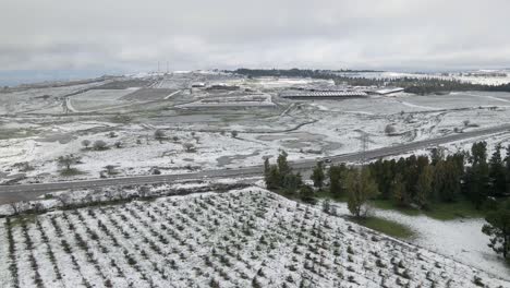 Drone-aerial-view-of-snow-covered-countryside-with-cars-travelling-on-road,-Israel