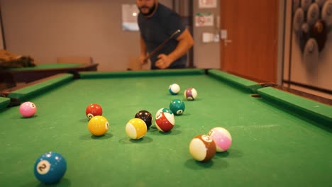 Casual-player-hitting-starting-position-shot-billiard-balls-triangle-white-cue-ball-seen-in-a-distance-sports-game-of-billiards-on-green-cloth