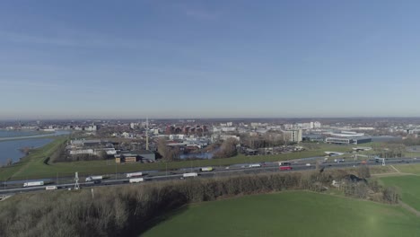 Drohnenaufnahme-Einer-Stadt-Und-Einer-Autobahn-Hinter-Grasfeldern