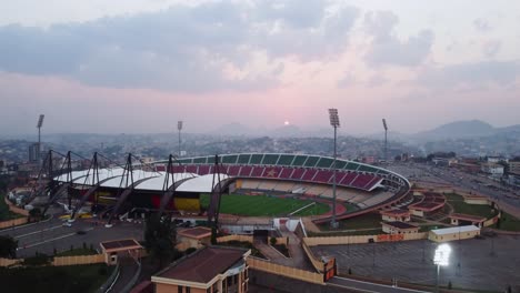 Aerial-view-towards-the-Stade-Omnisports-Ahmadou-Ahidjo-stadium,-sunset-in-Yaounde,-Cameroon