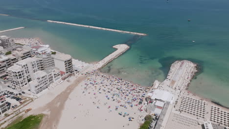 Aerial-footage-rotating-around-the-beach-and-the-green-Adriatic-Sea-showing-tourists-sunning-and-swimming-in-Bari,-Italy