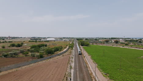 Static-aerial-footage-of-a-passenger-train-passing-underneath-in-Bari,-Italy