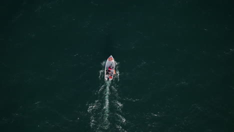 Top-down-aerial-footage-of-the-sea-with-a-small-boat-slowly-moving-through-the-choppy-waves