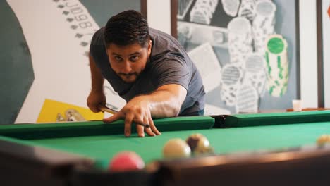 Young-man-playing-billiard-sinking-a-the-red-ball-to-the-pocket