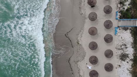 Bird's-Eye-View-Over-Beach-With-Parasols-On-The-Shore-In-Vama-Veche,-Romania---drone-shot