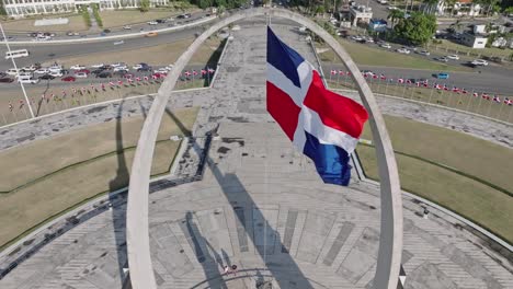 Bandera-Ondeando-En-El-Viento-En-El-Arco-Triunfal,-Plaza-De-La-Bandera-En-La-Ciudad-De-Santo-Domingo