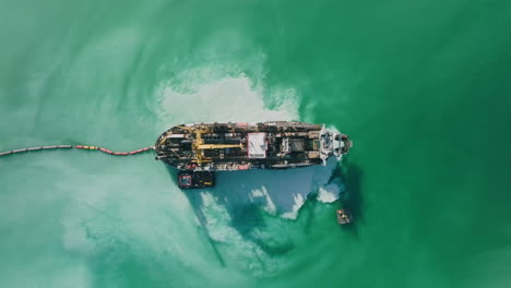 Wide-top-down-aerial-footage-of-a-ship-that-is-dredging-up-sand-in-the-harbor-of-Bari,-Italy
