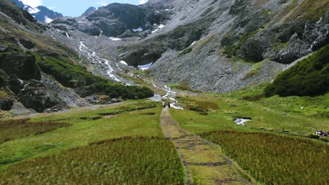 A-shot-of-people-walking-in-a-valley-landscape-with-a-glacier-and-snow-peaks