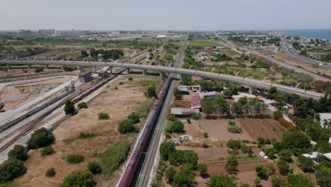 Aerial-footage-following-a-passenger-train-moving-north-away-from-the-town-of-Bari,-Italy