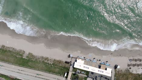 Top-Down-View-Of-Waves-Splashing-On-Sandy-Shore-In-Vama-Veche,-Romania---drone-shot