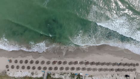Bird's-Eye-View-Of-Beach-With-Parasols-And-Sandy-Shore-In-Vama-Veche,-Romania---drone-shot