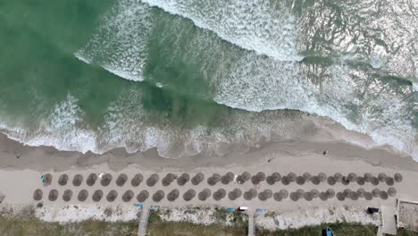 Top-Down-View-Of-Beach-With-Parasols-On-The-Shore-In-Vama-Veche,-Romania--drone-shot