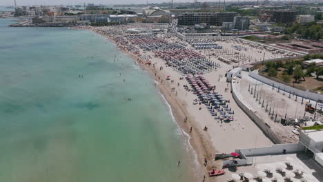 Aerial-footage-going-over-the-waves-on-the-beach-of-resorts-in-Bari,-Italy-during-the-day