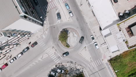 Fast-ascending-aerial-footage-of-a-roundabout-in-the-suburbs-of-Bari,-Italy-with-cars-moving-around-it