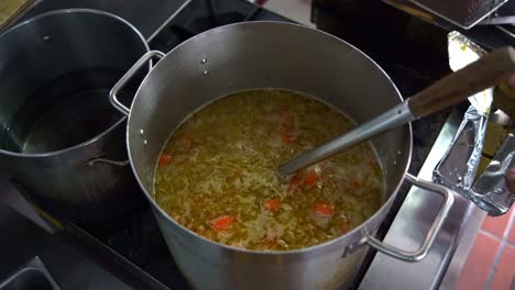 Chef-adding-blocks-of-Japanese-curry-roux-into-a-big-stock-pot-on-stovetop,-full-of-potatoes,-carrots-and-onions,-top-down-view