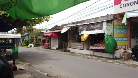 Scooters,-Motos-Y-Personas-Conduciendo-Bali-Road-En-Batubulan-Sukawati-Gianyar-Durante-El-Día,-Una-Calle-Local-En-Un-Pueblo-Tradicional-Balinés,-Indonesia,-Sudeste-Asiático