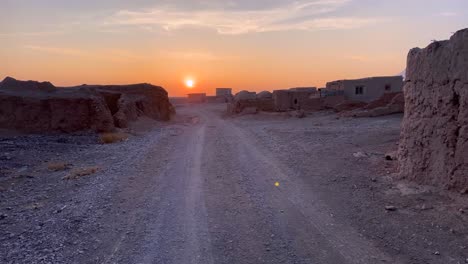 Sunset-in-desert-road-abandoned-town-in-remote-rural-area-in-Iran-Central-desert-with-hot-dry-climate-has-many-oasis-wildlife-species-and-flora-plant-vegetables-which-live-n-grow-by-rain-water-springs