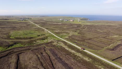 Tilting-drone-shot-of-a-peat-cutter-driving-his-tractor-full-of-peat-home-near-his-peatland