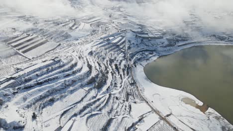 Panning-drone-aerial-view-of-terraced-farmland-at-Lake-Ram-after-snowstorm,-Israel