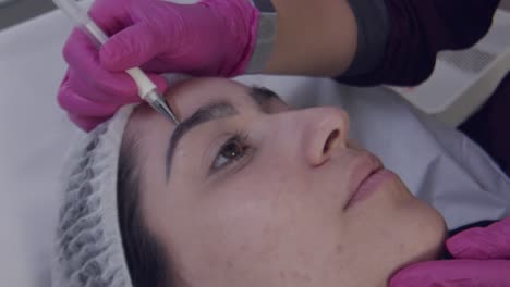 Close-up,-cosmetic-surgeon-marking-lines-on-botox-patient's-face