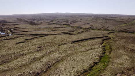Drone-shot-of-a-natural-peat-land,-containing-peat-banks-used-for-cutting-peat-for-fuel