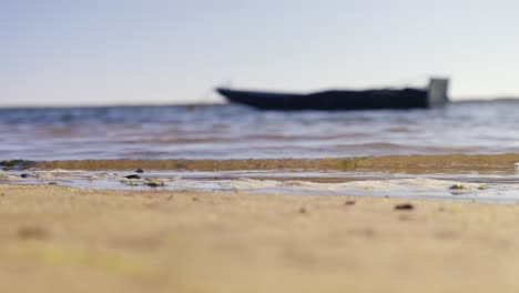 Sand-beach-and-boat-or-ship-on-sea-in-blurry-background,-copy-space-for-titles