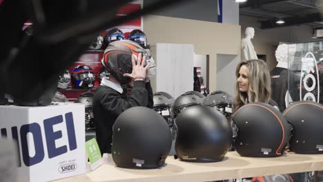 Eine-Verkäuferin-In-Einem-Geschäft-Für-Motorradzubehör-Lässt-Einen-Kunden-Helme-Testen