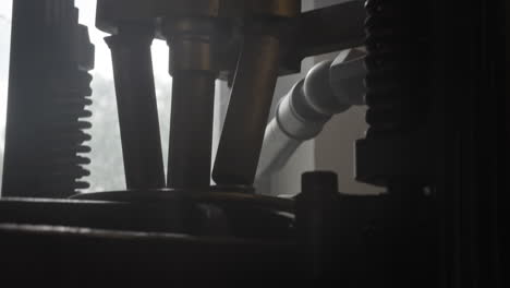 Close-up-shot-of-a-printing-machine-in-the-dark-with-some-light-source-from-behind