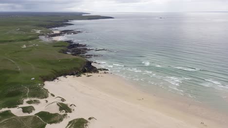 Drone-shot-of-Eoropie-beach-in-Ness-and-the-coastline-beyond-it-on-a-sunny,-Summer's-day