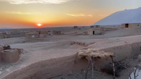 Old-traditional-desert-house-scattered-in-a-vast-land-Iran-sunset-color-sky-line-mountain-and-wide-horizon-view-in-the-background-landscape-people-was-living-in-this-rural-town-country-far-from-city