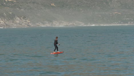 Instructor-teaches-power-hydrofoil-surfboard-off-mountainous-seashore