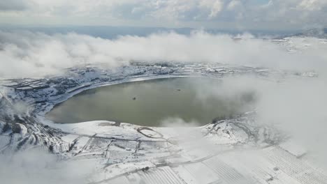 Static-drone-aerial-view-snow-covered-Lake-Ram-with-thick-low-level-clouds,-Israel